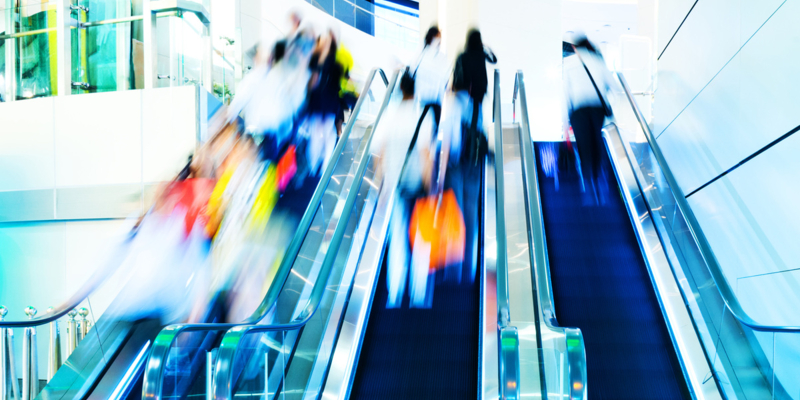 people rushing in escalators at a modern shopping mall.