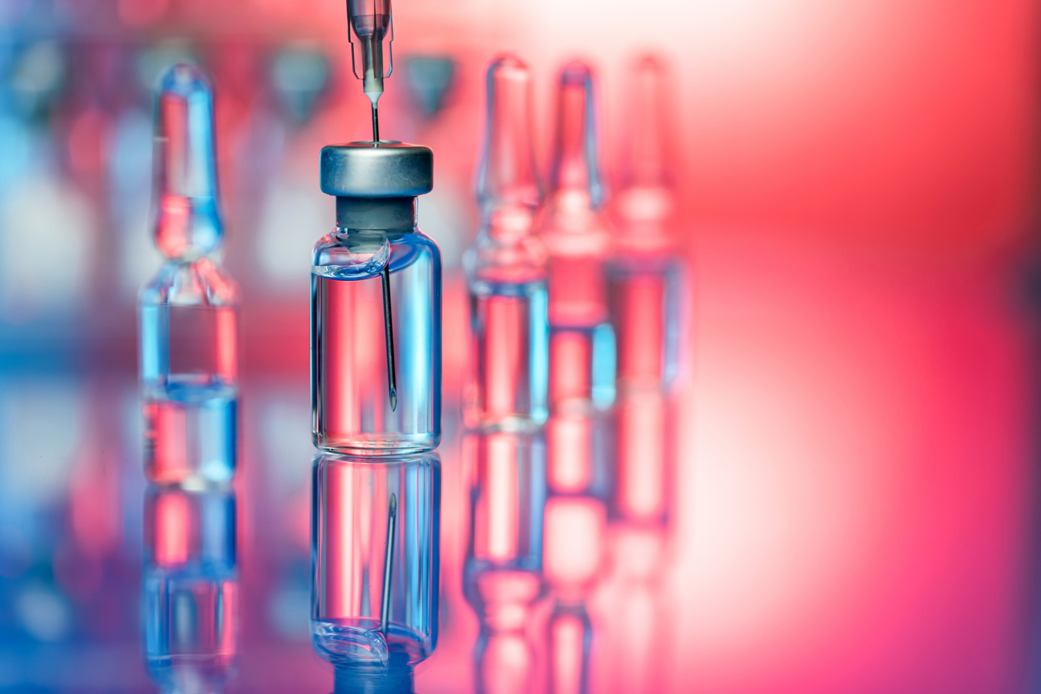 Close up shot of vaccines - glass bottles, ampules and syringe with needle. Good for illustration of flu shot, vaccination and covid-19