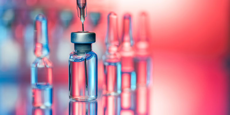 Close up shot of vaccines - glass bottles, ampules and syringe with needle. Good for illustration of flu shot, vaccination and covid-19