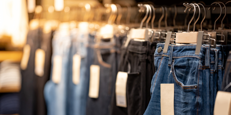 Jeans or Denim pants (trousers) hanging on rack in clothes shop. Fashion product collection in clothing store for selling. Textile industry and business concept