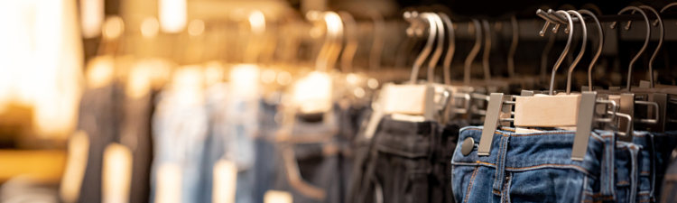 Jeans or Denim pants (trousers) hanging on rack in clothes shop. Fashion product collection in clothing store for selling. Textile industry and business concept