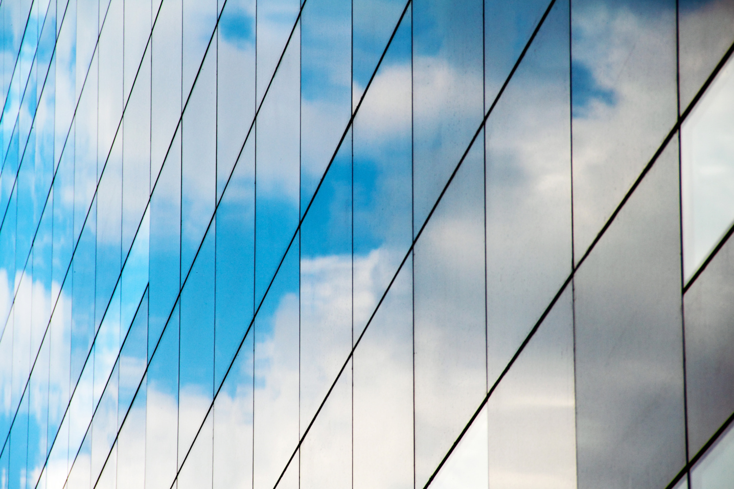 A reflection of clouds and sky in a mirrored glass building.