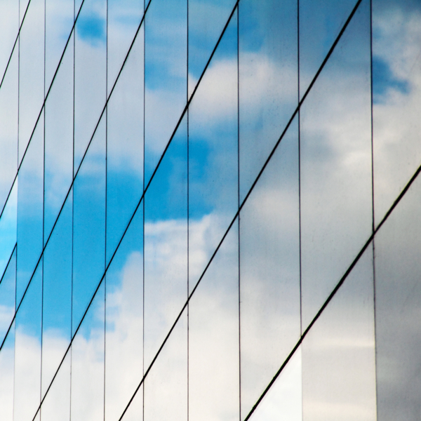 A reflection of clouds and sky in a mirrored glass building.