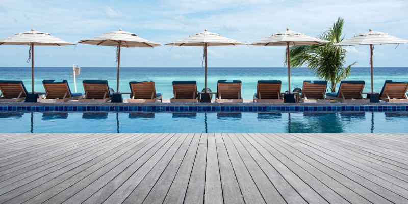 Wooden terrace beside tropical beach swimming pool