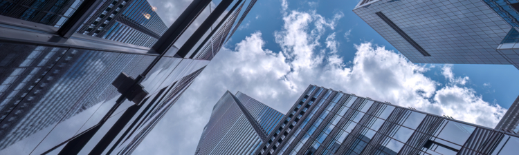 New York City - August 22, 2024: Looking up at tall buildings with clouds and blue sky reflected in the windows at 43rd Street and Madison Avenue in Manhattan. Looking directly overhead gives the feeling of falling into the sky especially as the sky is reflected in the glass on these buildings in midtown Manhattan.