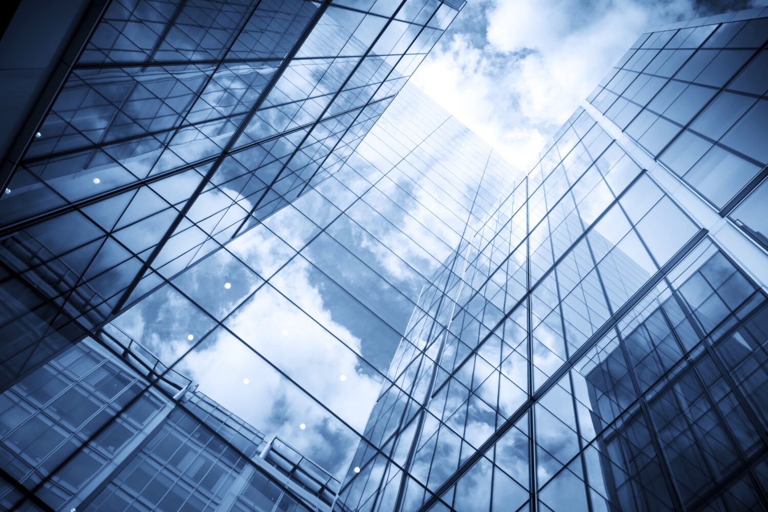 view of a contemporary glass skyscraper reflecting the blue sky and clouds