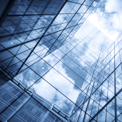 view of a contemporary glass skyscraper reflecting the blue sky and clouds