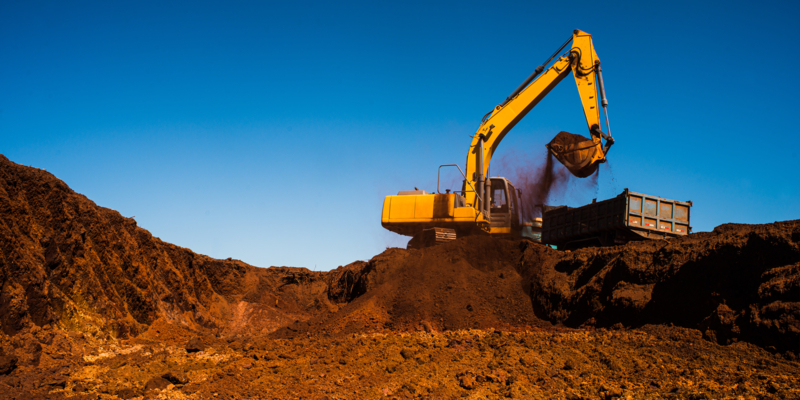 Backhoe machine performing excavation on a site.