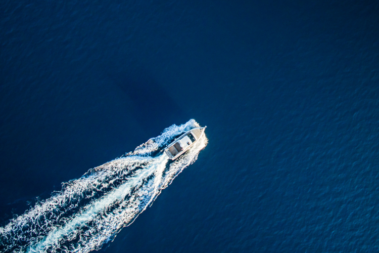 Fast speedboat racing along the open sea leaving white trail. High angle view from drone (quadcopter) Phantom 3.