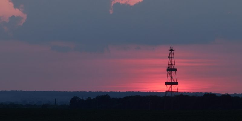 Gas production, oil production. Drilling rig against the setting sun